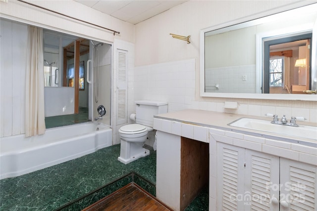 full bathroom featuring vanity, toilet, washtub / shower combination, and tile walls