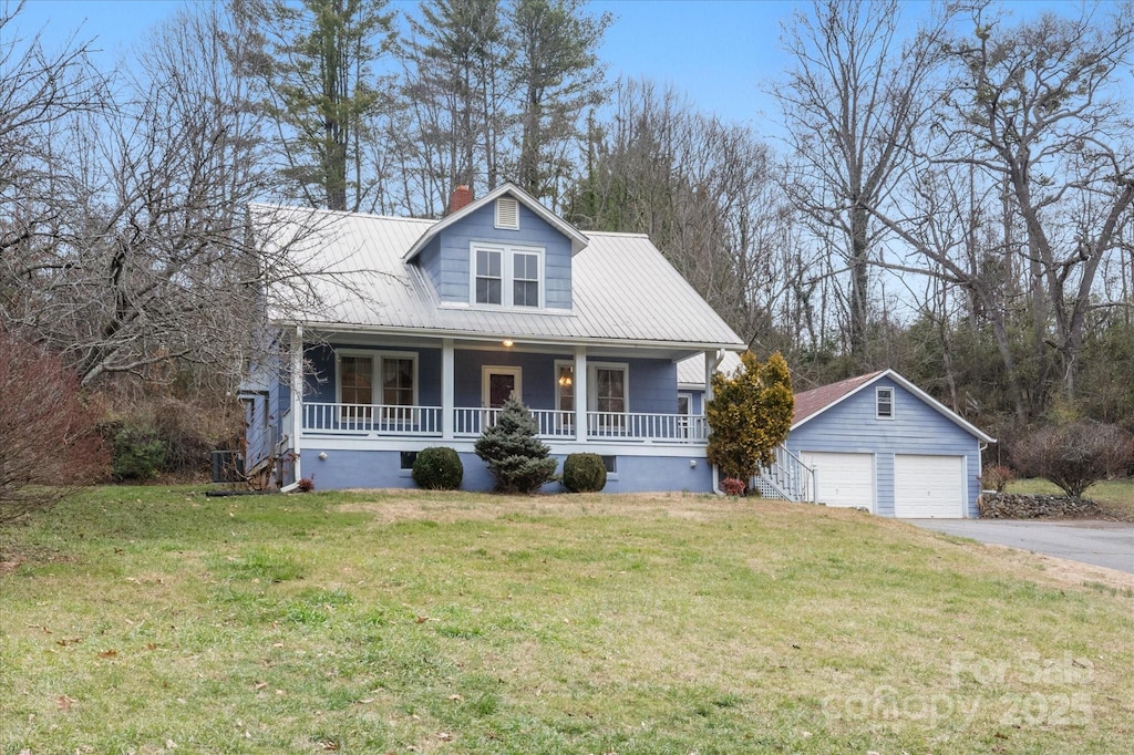 view of front of home featuring a porch, an outbuilding, a front yard, and a garage