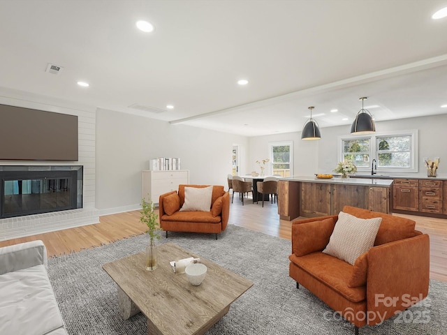 living room with light hardwood / wood-style floors and a brick fireplace