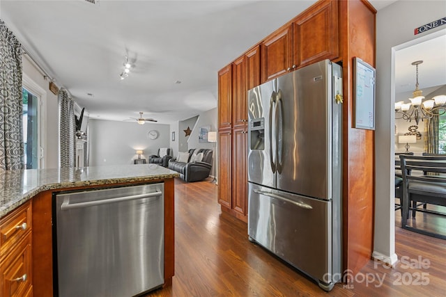 kitchen featuring a healthy amount of sunlight, light stone countertops, stainless steel appliances, and ceiling fan with notable chandelier