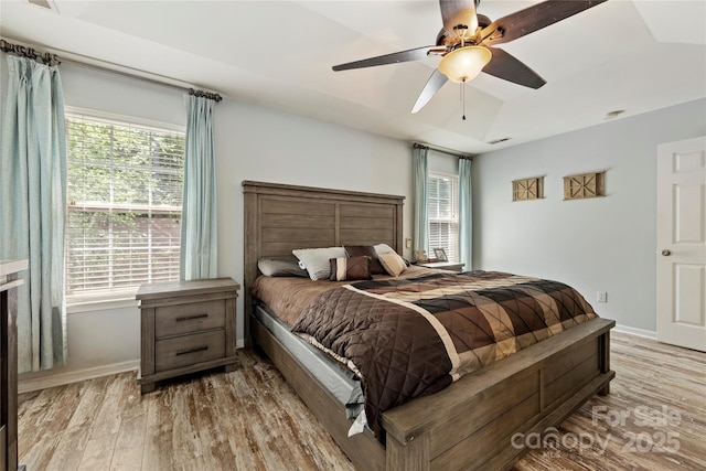 bedroom featuring ceiling fan, multiple windows, and light hardwood / wood-style flooring