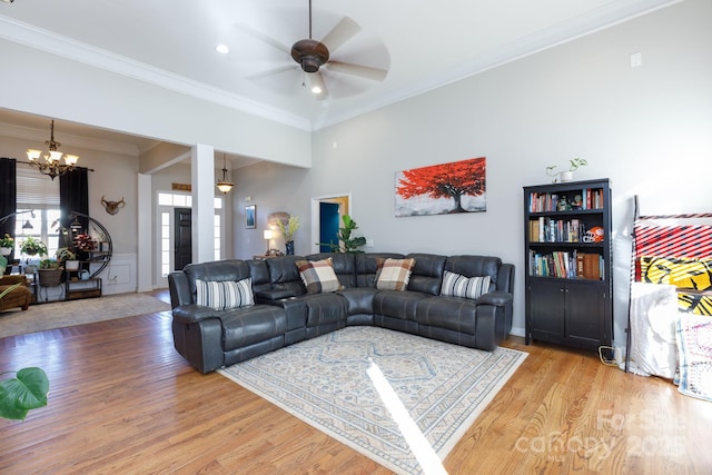 living room with ceiling fan with notable chandelier, hardwood / wood-style flooring, and crown molding