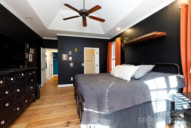 bedroom featuring light hardwood / wood-style flooring, a raised ceiling, ceiling fan, and crown molding