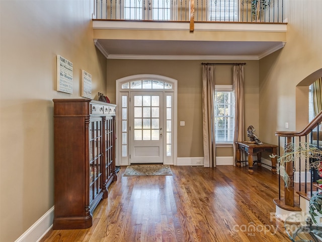 foyer entrance featuring a high ceiling, crown molding, and wood-type flooring