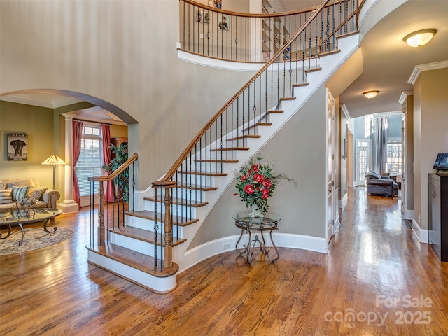 stairs featuring a high ceiling, hardwood / wood-style floors, and ornamental molding