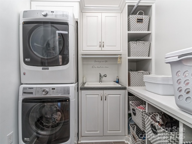 laundry area featuring stacked washing maching and dryer, cabinets, and sink