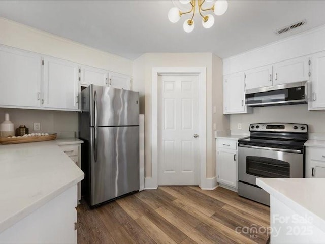 kitchen featuring white cabinetry, appliances with stainless steel finishes, dark hardwood / wood-style floors, and an inviting chandelier