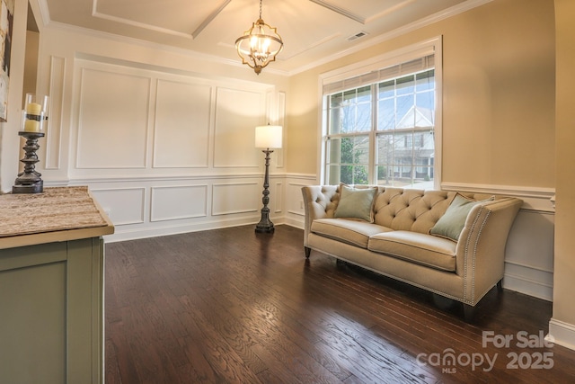 sitting room featuring a decorative wall, dark wood-style flooring, visible vents, an inviting chandelier, and crown molding