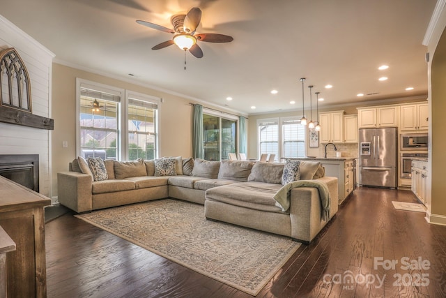 living area featuring a large fireplace, recessed lighting, dark wood finished floors, and crown molding