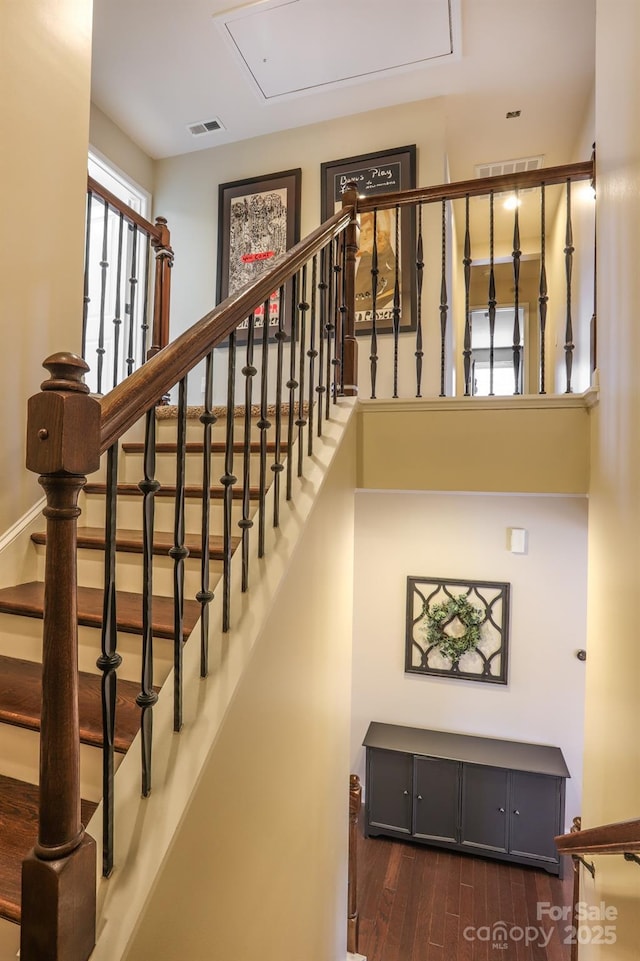 stairs with attic access, visible vents, and wood finished floors