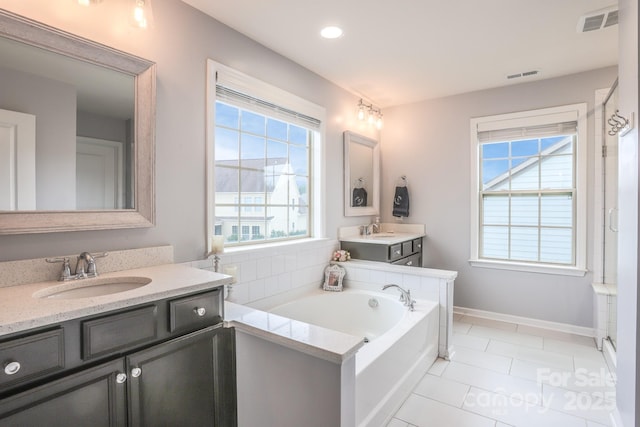 bathroom with a garden tub, a sink, and visible vents