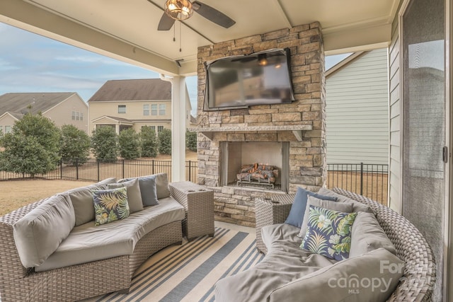 view of patio / terrace with an outdoor living space with a fireplace, fence, and ceiling fan