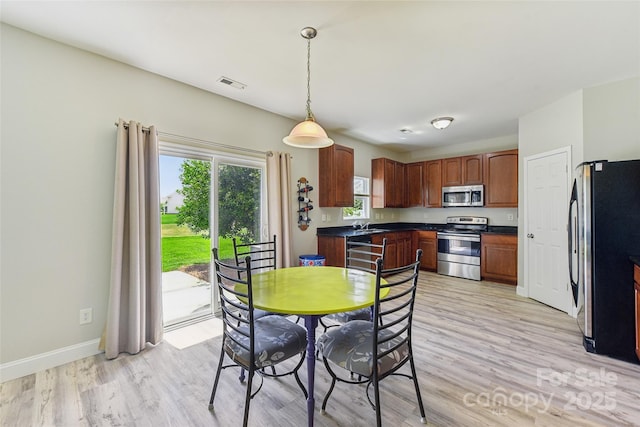 kitchen featuring light hardwood / wood-style flooring, decorative light fixtures, and appliances with stainless steel finishes