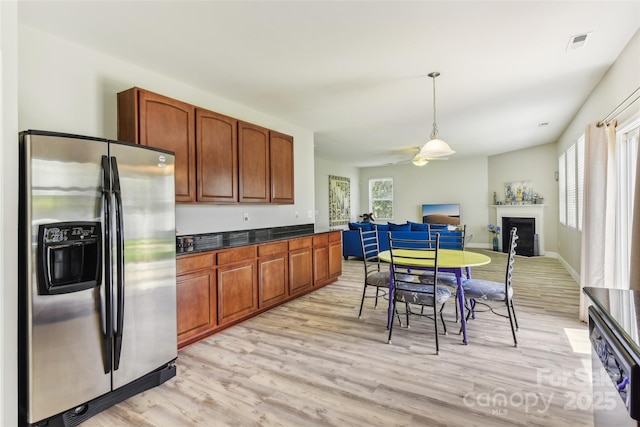 kitchen featuring ceiling fan, light wood-type flooring, stainless steel refrigerator with ice dispenser, and hanging light fixtures