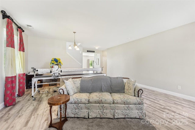 living room with light hardwood / wood-style floors and a notable chandelier