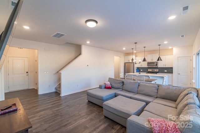 living room with dark wood-type flooring, recessed lighting, visible vents, and stairs