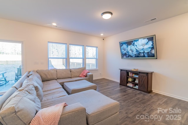 living room featuring a healthy amount of sunlight, baseboards, visible vents, and dark wood-type flooring