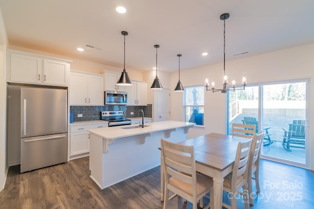 kitchen featuring light countertops, visible vents, backsplash, appliances with stainless steel finishes, and a sink