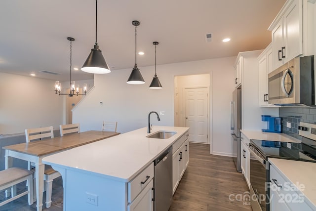 kitchen featuring a center island with sink, stainless steel appliances, decorative backsplash, white cabinets, and a sink