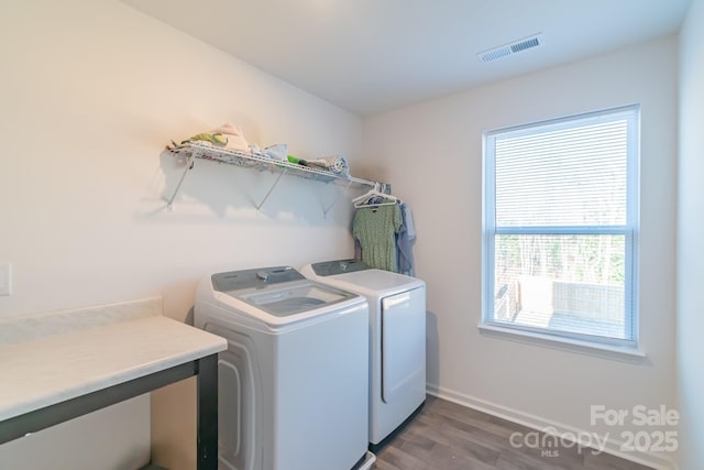 laundry room with visible vents, washing machine and dryer, wood finished floors, laundry area, and baseboards