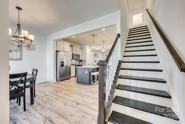 stairway with hardwood / wood-style floors, a notable chandelier, and sink