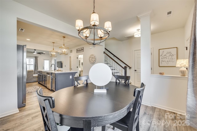 dining space with ceiling fan with notable chandelier, light hardwood / wood-style floors, and sink