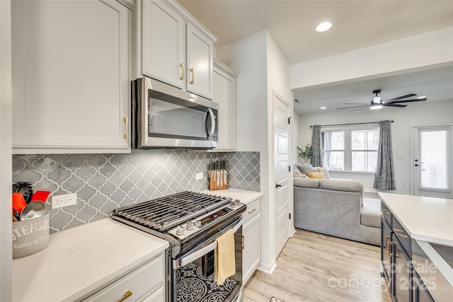 kitchen featuring decorative backsplash, appliances with stainless steel finishes, ceiling fan, light hardwood / wood-style flooring, and white cabinets