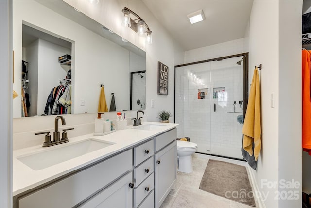 bathroom with tile patterned flooring, vanity, toilet, and a shower with door