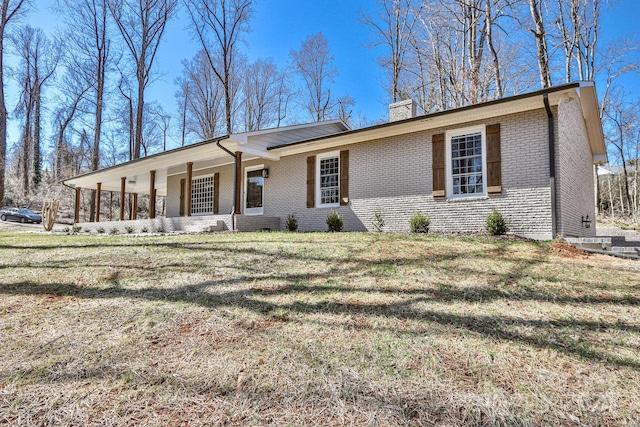 ranch-style house with a chimney, a front lawn, and brick siding