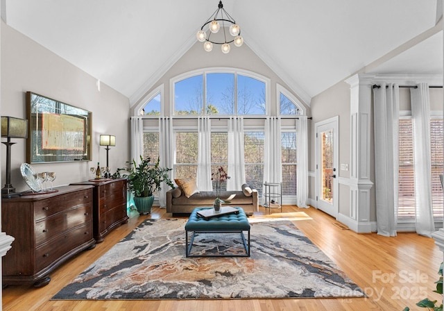 sitting room with high vaulted ceiling, an inviting chandelier, and light wood-type flooring