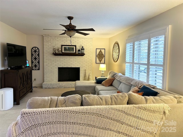 living room with ceiling fan, light colored carpet, a textured ceiling, and a brick fireplace