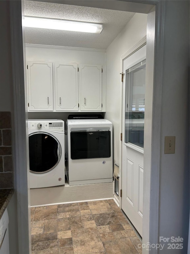 clothes washing area with cabinets, a textured ceiling, and separate washer and dryer