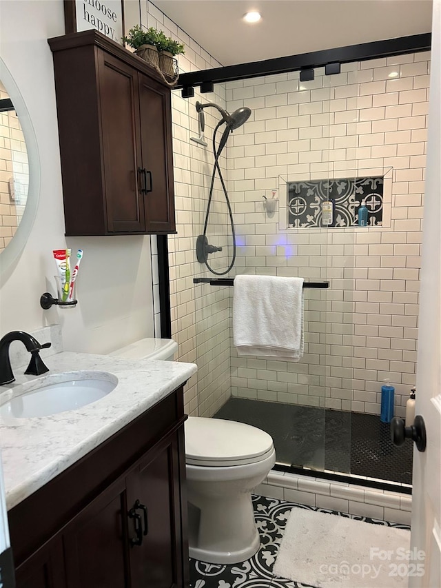 bathroom with tile patterned flooring, vanity, toilet, and walk in shower