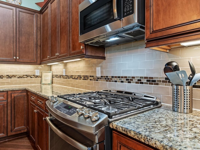 kitchen with backsplash, light stone counters, and stainless steel appliances