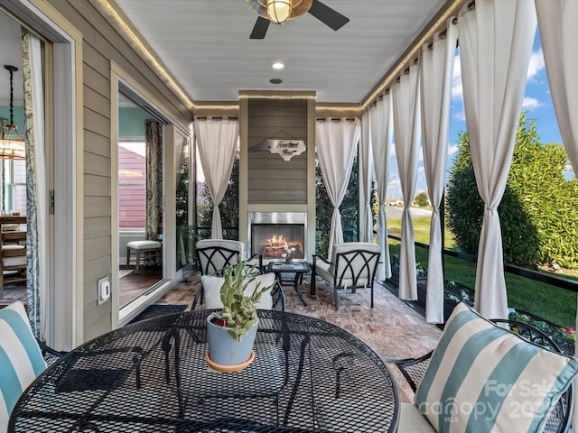 sunroom featuring ceiling fan and an outdoor fireplace