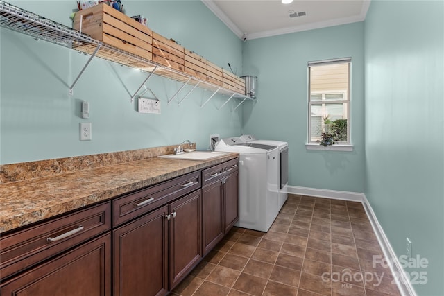 clothes washing area with cabinets, washer and dryer, ornamental molding, and sink