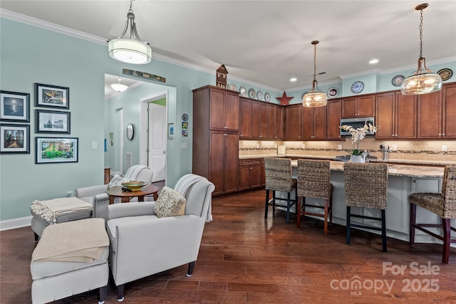 kitchen featuring a kitchen bar, light stone counters, tasteful backsplash, and pendant lighting