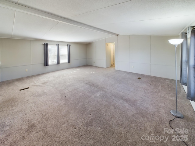 carpeted spare room with lofted ceiling with beams and a textured ceiling