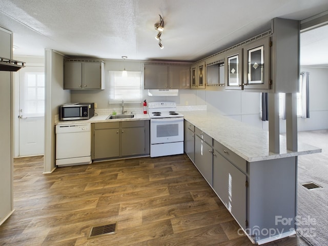 kitchen featuring sink, a textured ceiling, dark hardwood / wood-style floors, kitchen peninsula, and white appliances