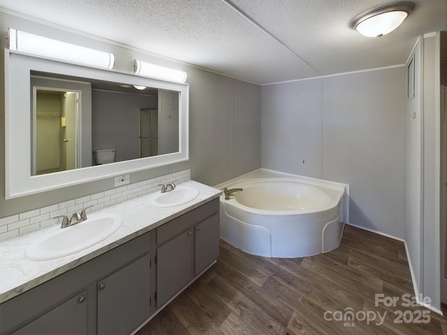 bathroom with hardwood / wood-style floors, decorative backsplash, a tub to relax in, vanity, and a textured ceiling