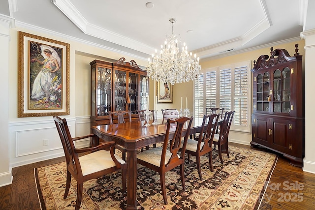 dining room with a raised ceiling, dark hardwood / wood-style flooring, crown molding, and a chandelier