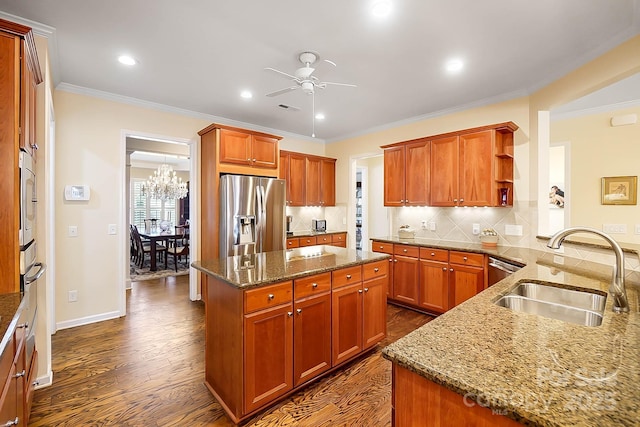 kitchen with sink, light stone counters, decorative backsplash, a kitchen island, and appliances with stainless steel finishes