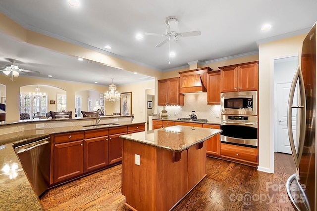 kitchen with appliances with stainless steel finishes, a kitchen breakfast bar, premium range hood, sink, and a kitchen island