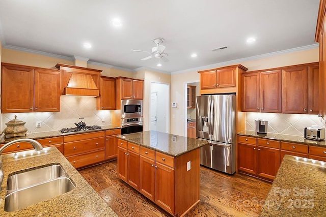 kitchen with light stone countertops, appliances with stainless steel finishes, a kitchen island with sink, dark wood-type flooring, and sink