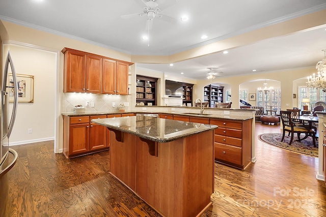 kitchen with a center island, crown molding, sink, dark stone countertops, and a kitchen bar