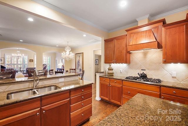 kitchen featuring light stone countertops, sink, hardwood / wood-style flooring, an inviting chandelier, and stainless steel gas stovetop