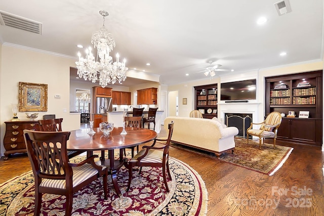 dining room with dark hardwood / wood-style flooring, ceiling fan with notable chandelier, and ornamental molding