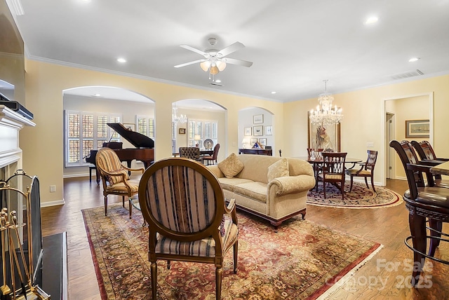 living room featuring ceiling fan with notable chandelier, dark hardwood / wood-style floors, and ornamental molding