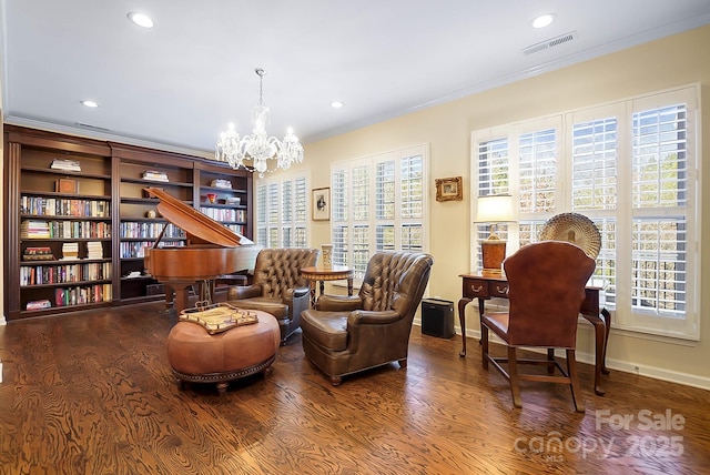 sitting room featuring hardwood / wood-style flooring, ornamental molding, and an inviting chandelier