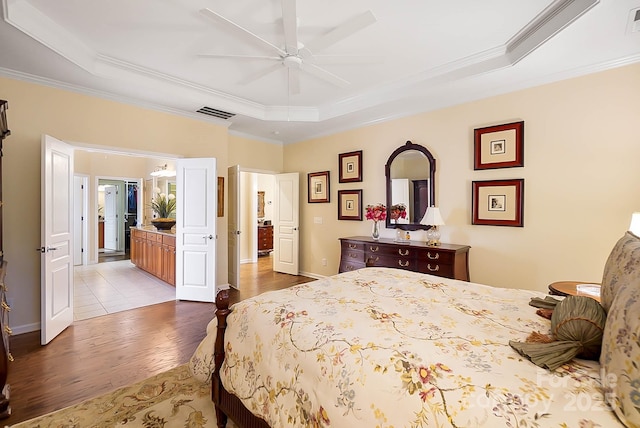 bedroom with a tray ceiling, ceiling fan, ornamental molding, and light hardwood / wood-style floors